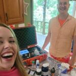 A woman and man are smiling in front of an open suitcase.